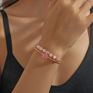 Elegant gold wire-wrapped bangle with pink cat eye stones worn on wrist with shadow effects