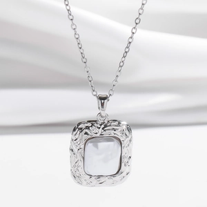 Collana con ciondolo geometrico in argento e inserto in perla su sfondo di raso bianco