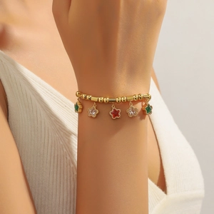 Bracelet pour femme en or avec breloques étoiles et zircons colorés porté au poignet