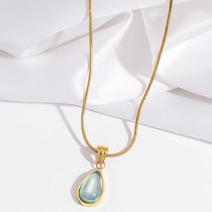 Detailed view of water-drop blue gemstone pendant on a golden snake bone chain necklace