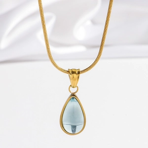 Elegant gold snake chain necklace with a vintage blue teardrop pendant on white silk