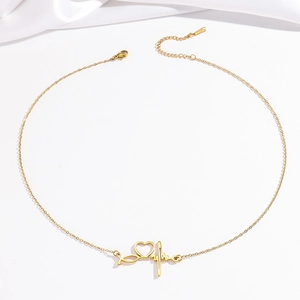 Elegant gold heartbeat necklace with heart pendant on white silk fabric background