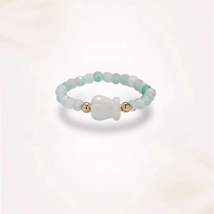 Detail of beaded flower ring with freshwater pearls and green gemstones on white background