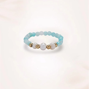 Close-up of handmade ring with blue faceted beads, gold accents and white pearls