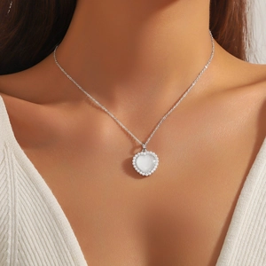 Collana a cuore in argento con pendente bianco e perline indossata da una donna