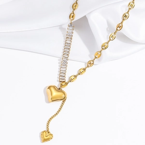Detailed view of golden heart pendant necklace with zircon chain on white silk