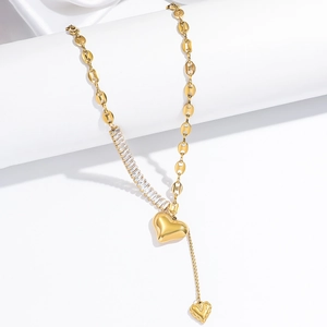Golden heart pendant necklace with asymmetrical zircon chain on white background
