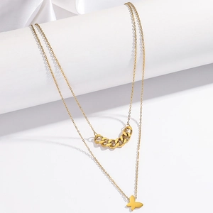 Détail d'un collier doré double épaisseur avec pendentif papillon et maillons cubains