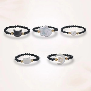 Five-piece black spinel bead rings set with pearl, moon and star accents on pink background