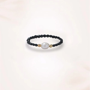 Detailed view of beaded ring with black faceted stones, white pearl and gold accents