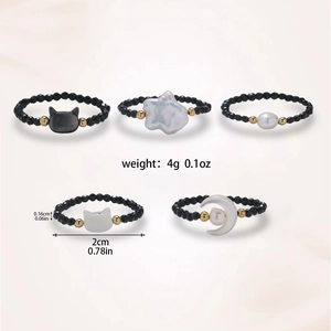 Detailed view of 5-piece black beaded rings set with moon and pearl charms