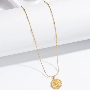 Dettaglio della collana con ciondolo ottagonale dorato e rilievo vintage su seta bianca
