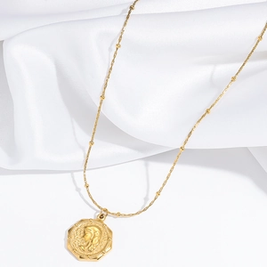 Collana vintage dorata con ciondolo ottagonale goffrato su raso bianco