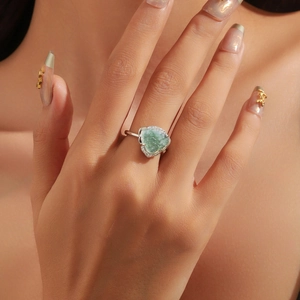 Macro shot of silver ring with green carved jade buddha and sparkling zircon halo