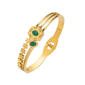 Detail of gold-plated bangle featuring green gemstones and hexagon star pattern accents