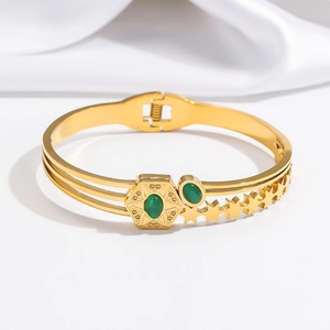 Detail of gold-tone bracelet with emerald green stones and pentagram hollow patterns