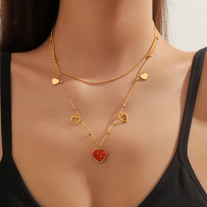 Collana a doppio strato dorata con cuori traforati e ciondolo in zircone rosso su modella