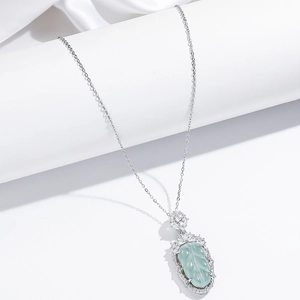Macro detail of leaf-shaped jade pendant with sparkling cubic zirconia on silver chain