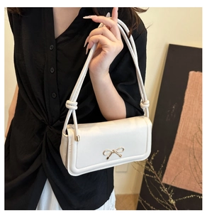 Détail du sac à bandoulière blanc avec nœud doré et sangle à nœuds tressés