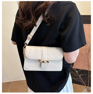 Close-up of white crocodile pattern embossed leather texture and gold metal turn-lock buckle