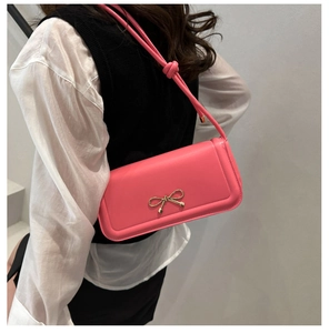 Détail d'un sac rose avec nœud doré en métal et design de bandoulière nouée