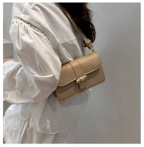 Detail of beige faux crocodile texture bag with golden bamboo clasp and adjustable strap