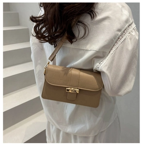Close-up of khaki crocodile pattern handbag with elegant gold bamboo buckle detail