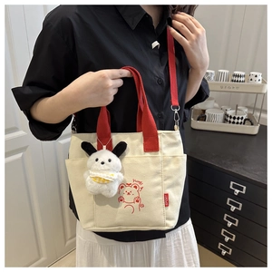Détail du sac en toile beige avec anses rouges, imprimé ours et charm chien en peluche
