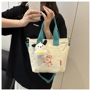 Détail du sac cabas en toile avec anses bleues, imprimé ours et charm peluche chien