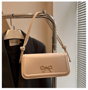 Détail d'un sac à main beige avec fermoir nœud papillon et bandoulière à nœud élégant