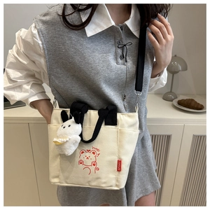 Detail of canvas bag with cute cartoon bear print and plush bunny charm accessory