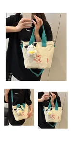 Détail du sac en toile avec anses vertes, imprimé ours et breloque chien en peluche