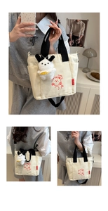 Vue détaillée du sac en toile crème avec imprimé ours et bandoulière noire amovible