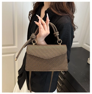 Détails de la texture gaufrée géométrique dorée et des anneaux métalliques de ce sac à main