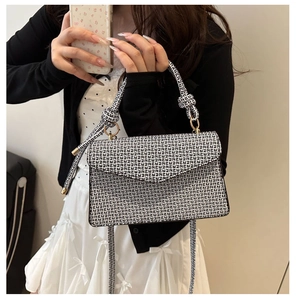 Détail du sac bandoulière à motifs géométriques noir et blanc avec poignée dorée