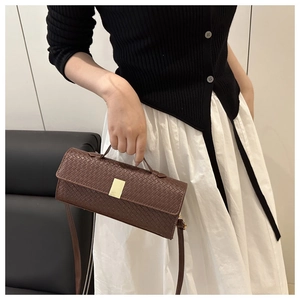 Detail of dark brown woven handbag with gold buckle and adjustable crossbody strap