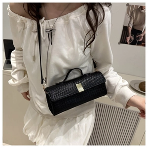 Close-up of black woven texture crossbody bag with elegant gold metal buckle detail