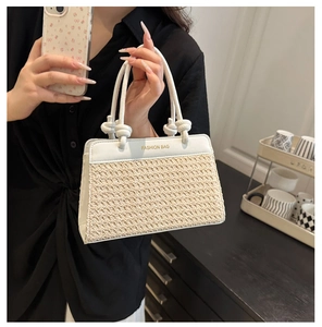 Detail der gewebten Strohtasche mit weißem Lederbesatz und geknotetem Seilgriff