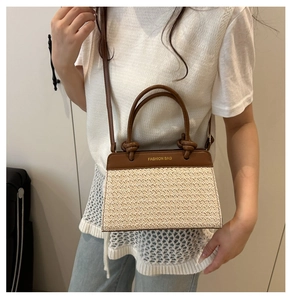 Detail einer gewebten Strohtasche mit braunem Lederbesatz und FASHION BAG Text am Modell