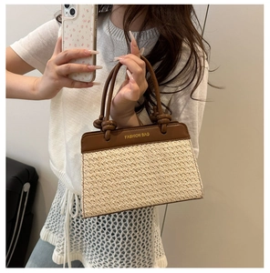Detail der gewebten Strohtasche mit braunen Ledergriffen und FASHION BAG Textaufdruck