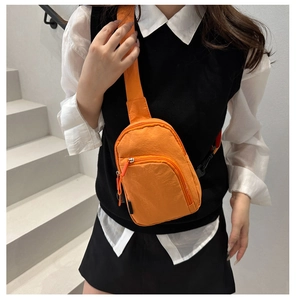 Détail d'un sac bandoulière en nylon orange vif avec sangle réglable porté par un mannequin