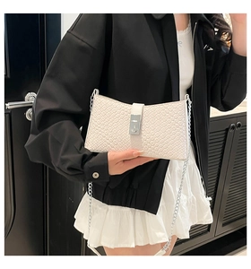 Close-up of white woven leather underarm bag with silver chain and square buckle