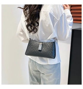 Detail of black crocodile textured shoulder bag with silver chain strap and metal clasp