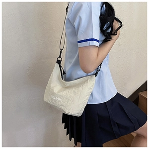 Close-up of beige wrinkled fabric crossbody bag with FASHION logo and black strap
