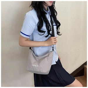 Detail of grey nylon crossbody bag with FASHION print paired with school style outfit