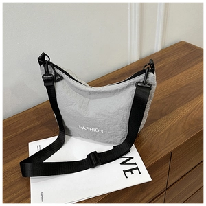 Detailed view of grey nylon crescent bag with FASHION text and adjustable black strap