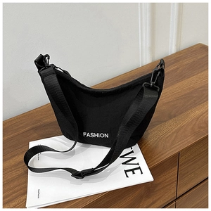Detail of black nylon hobo bag with Fashion logo print on white magazine prop