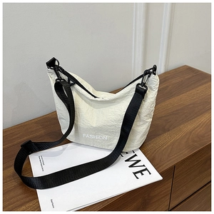 Detail of off-white pleated shoulder bag with fashion text and adjustable black strap