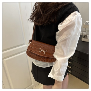Dettaglio borsa a tracolla marrone vintage texture coccodrillo con fiocco argento