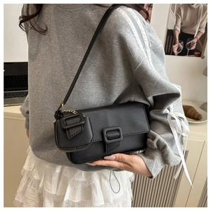 Close-up of black lychee texture baguette bag with mini pouch detail on a model